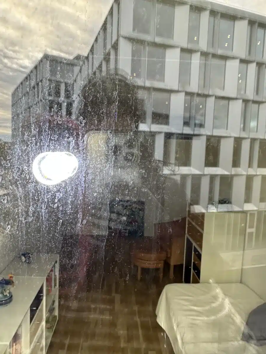 Kalk og aflejringer fra betonfacaden på en rude i Kongens Lyngby før glaspolering