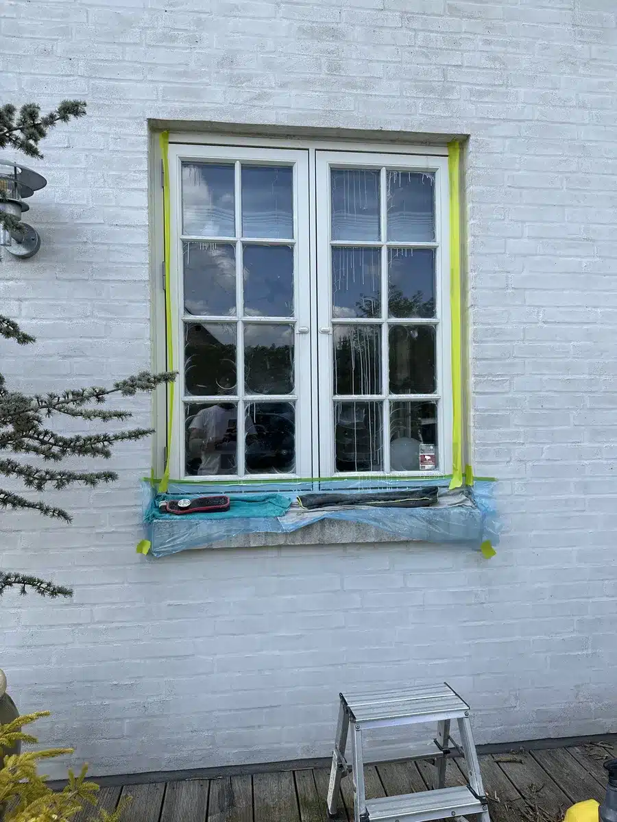 Afdækket vindue i Valby, hvor kalk fra facaden blev poleret væk